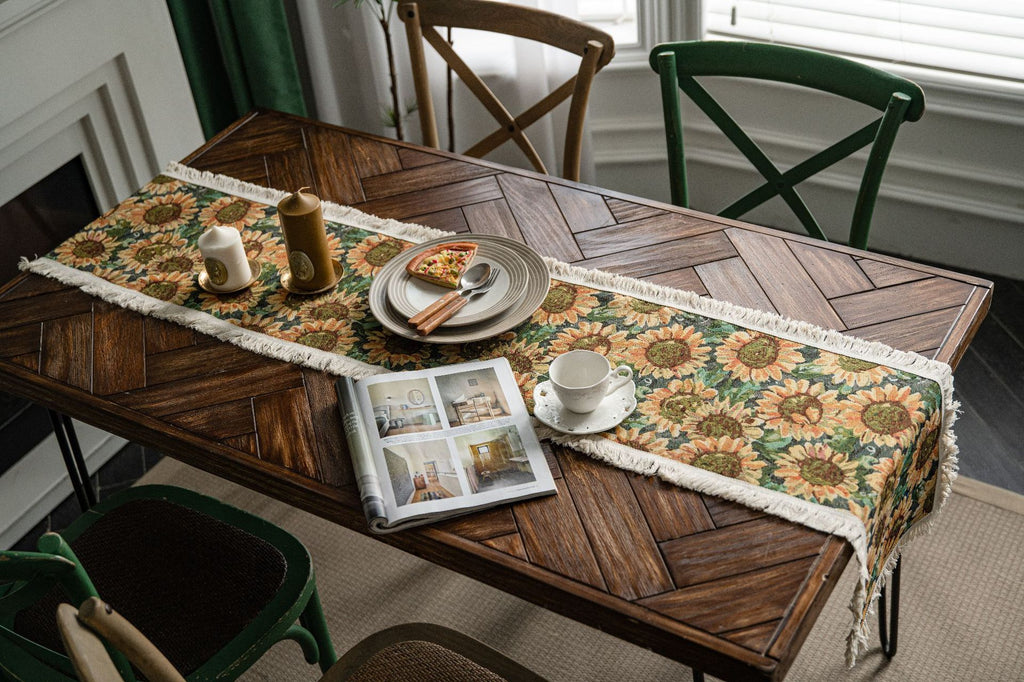 Wooden dining table with a sunflower-patterned table runner, plates, and a magazine.