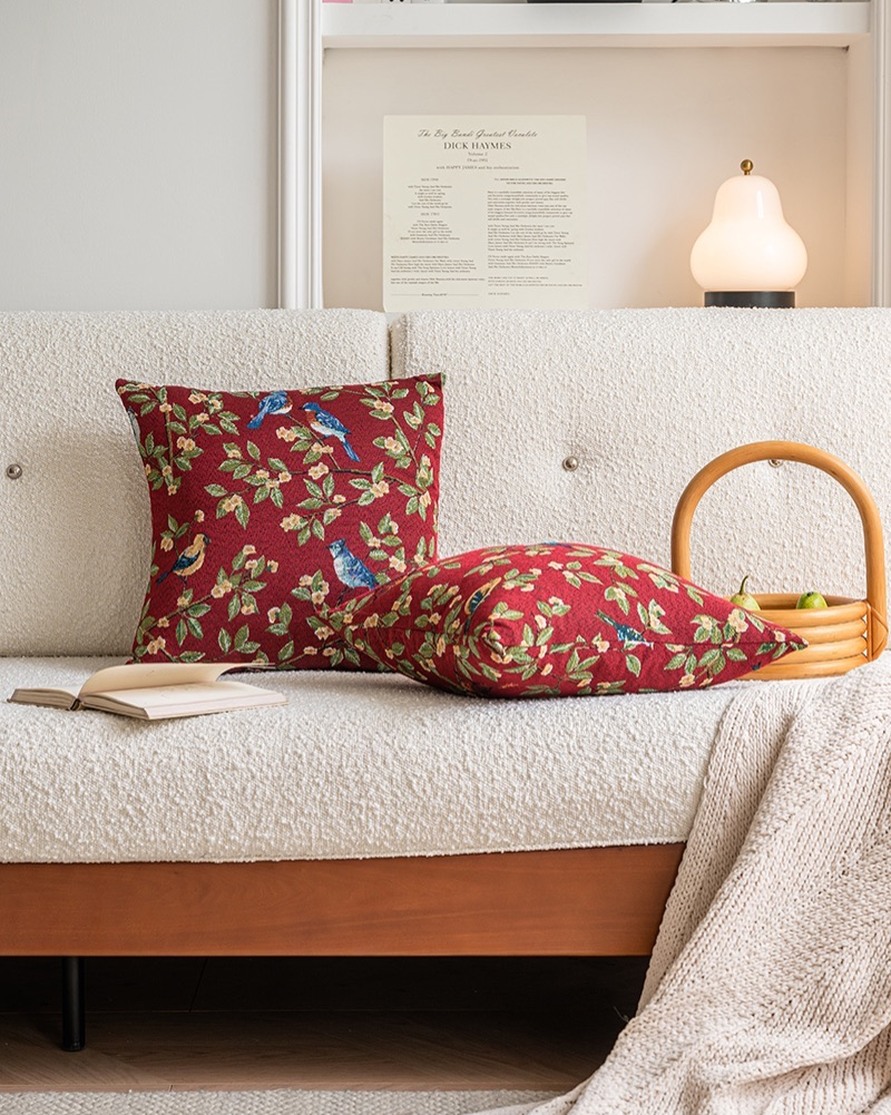 Decorative pillows with floral and bird pattern on a white sofa.