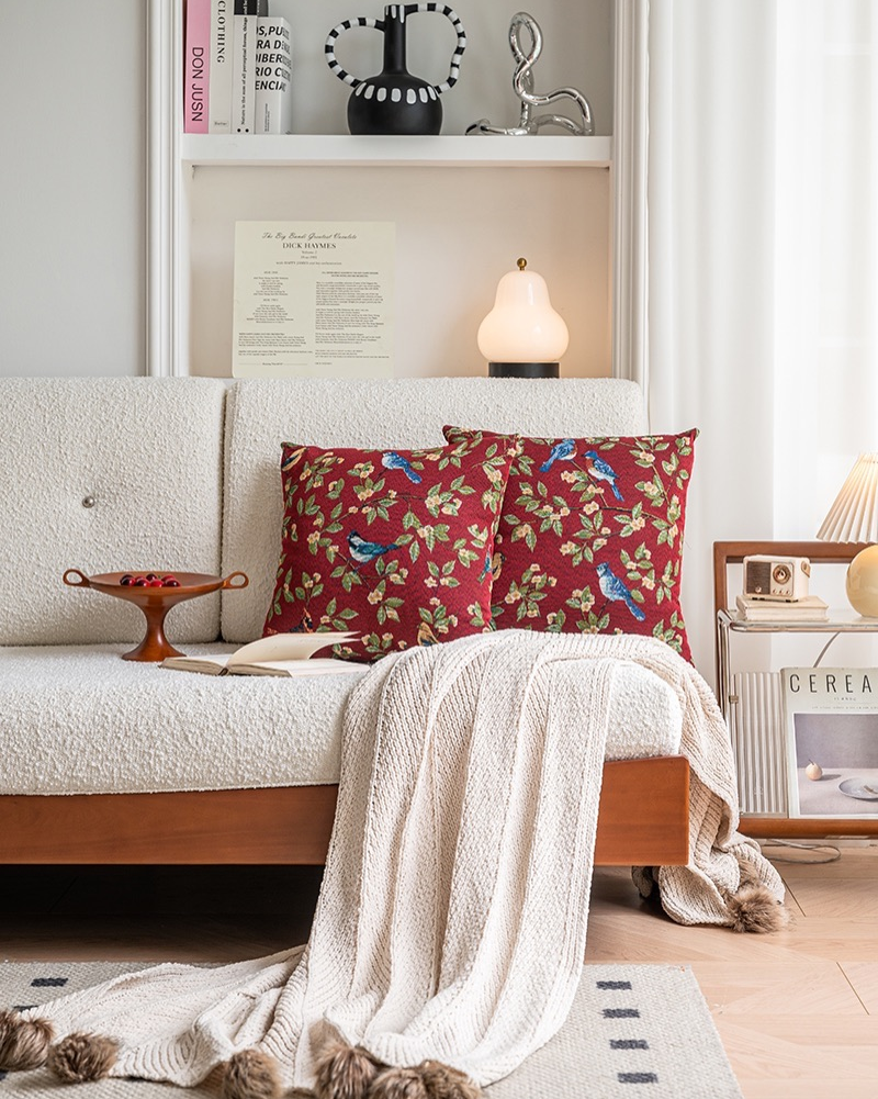Decorative pillows with floral and bird pattern on a sofa in a living room setting.
