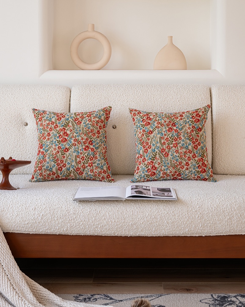Two red wildflower pillow covers styled on a sofa