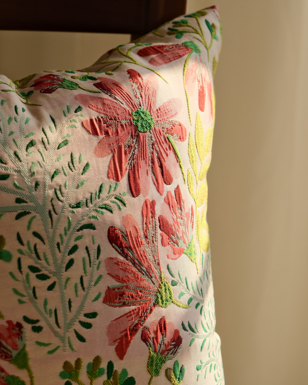Close-up of pink daisy embroidered floral on cream cushion