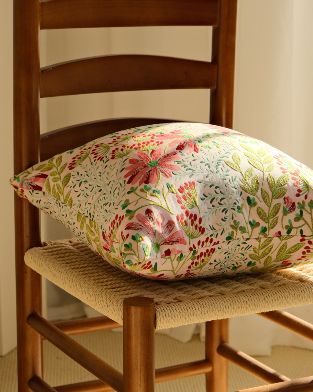 Pink floral embroidered cushion on a wooden chair, cottage