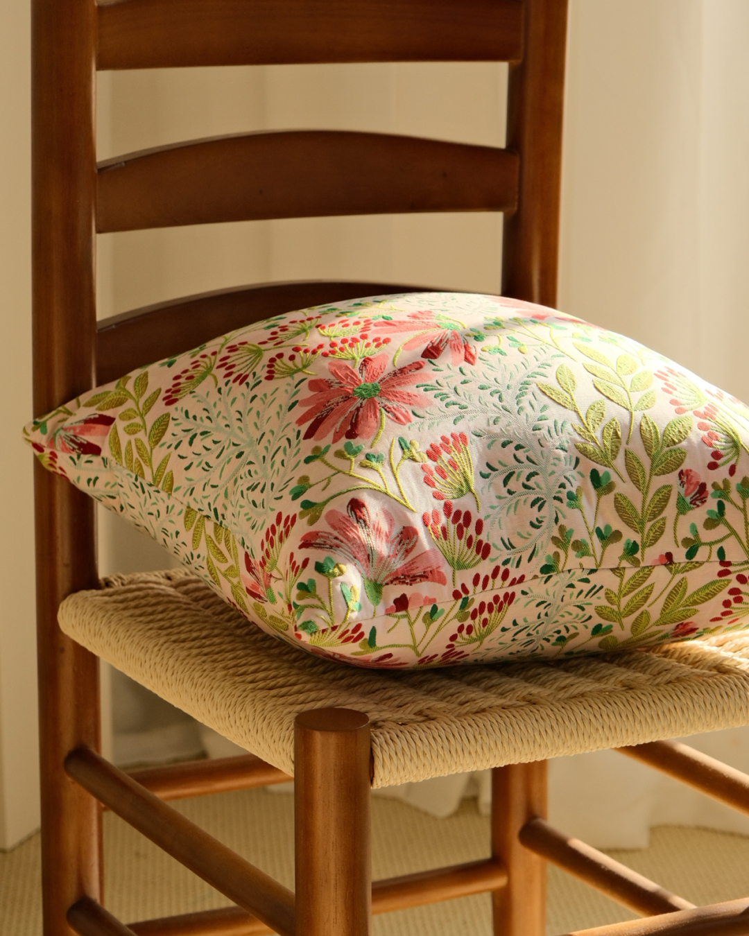 Pink floral embroidered cushion on a wooden chair, cottage