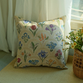 Watercolor floral cushion cover on a rug near a wooden cabinet