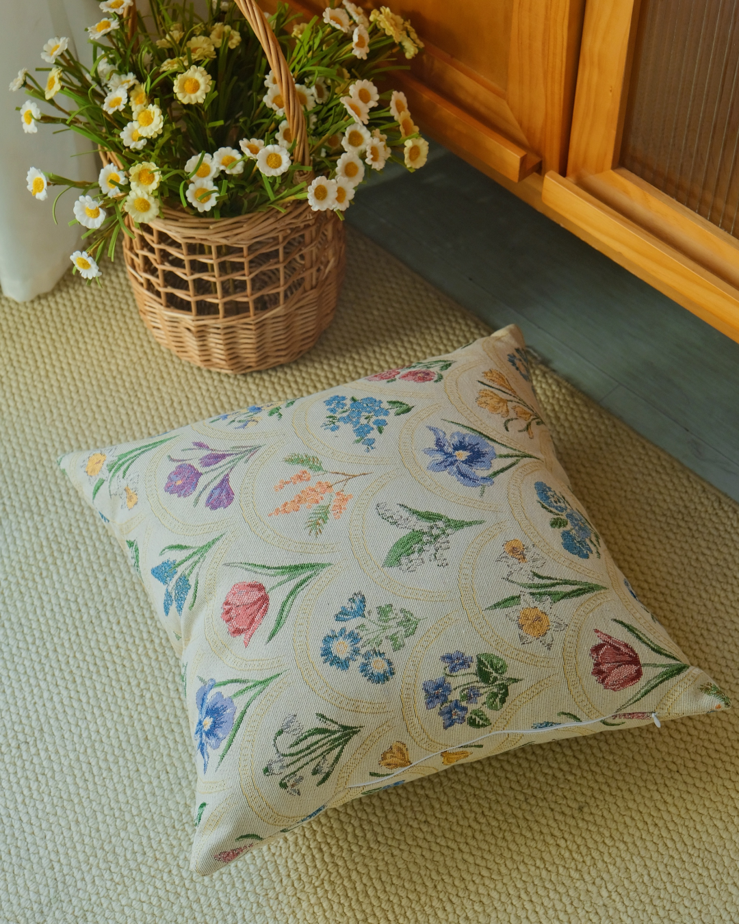 Watercolor floral cushion cover styled with a wicker basket of flowers