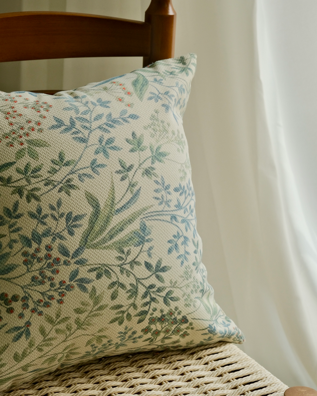 Sage botanical pillow cover on a chair with curtain background