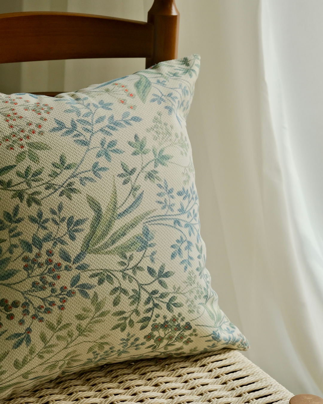 Sage botanical pillow cover on a chair with curtain background
