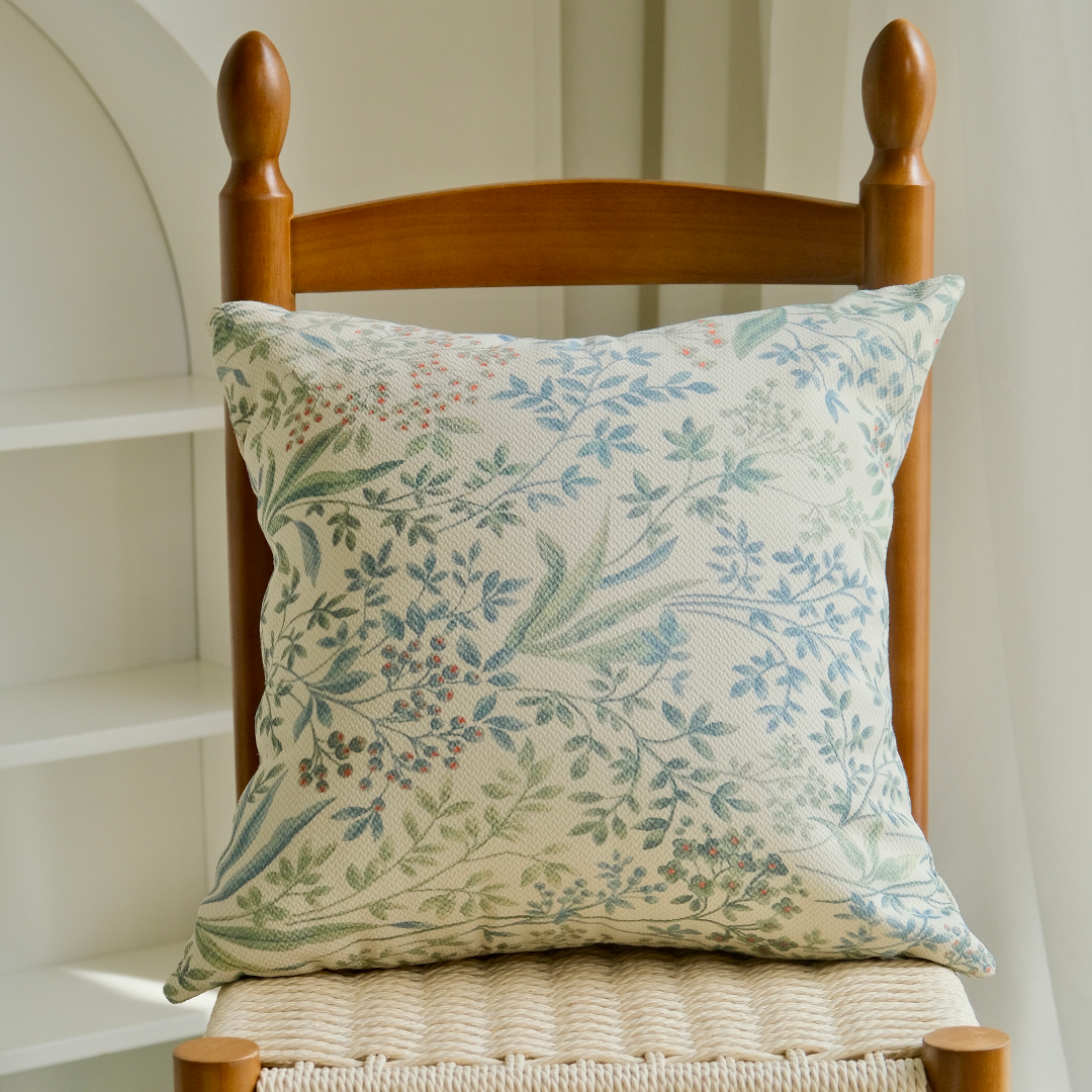 Sage botanical sprig pillow cover on a wooden chair with woven seat