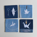 Flat lay of four indigo blue coasters with crane, key, swan, and boat motifs