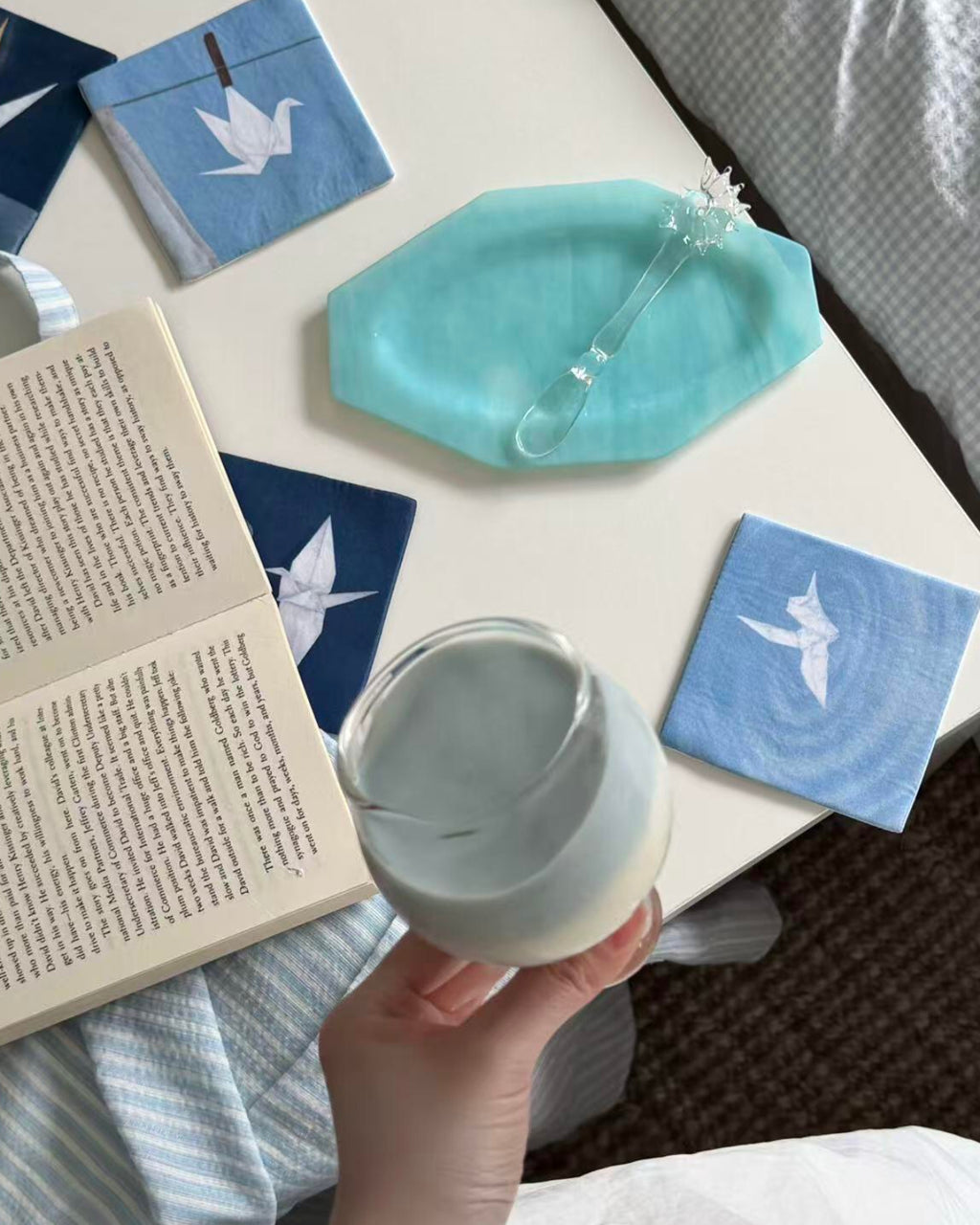 Hand placing a white mug on an indigo crane motif coaster