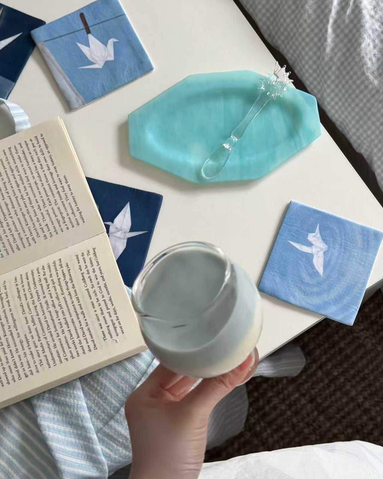 Hand placing a white mug on an indigo crane motif coaster