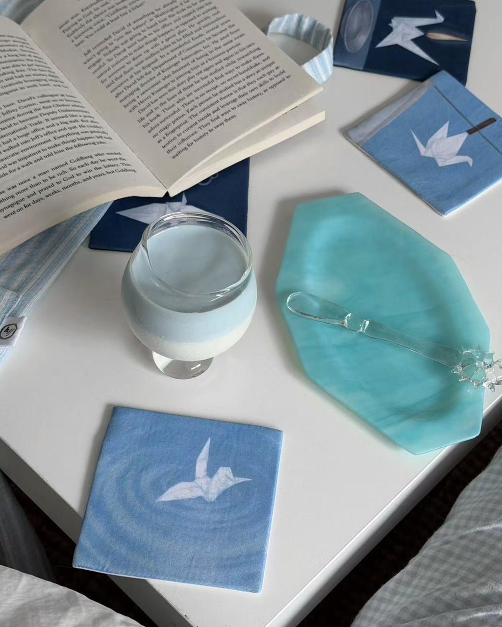 Indigo coaster set on a bed tray with a glass of milk and open book