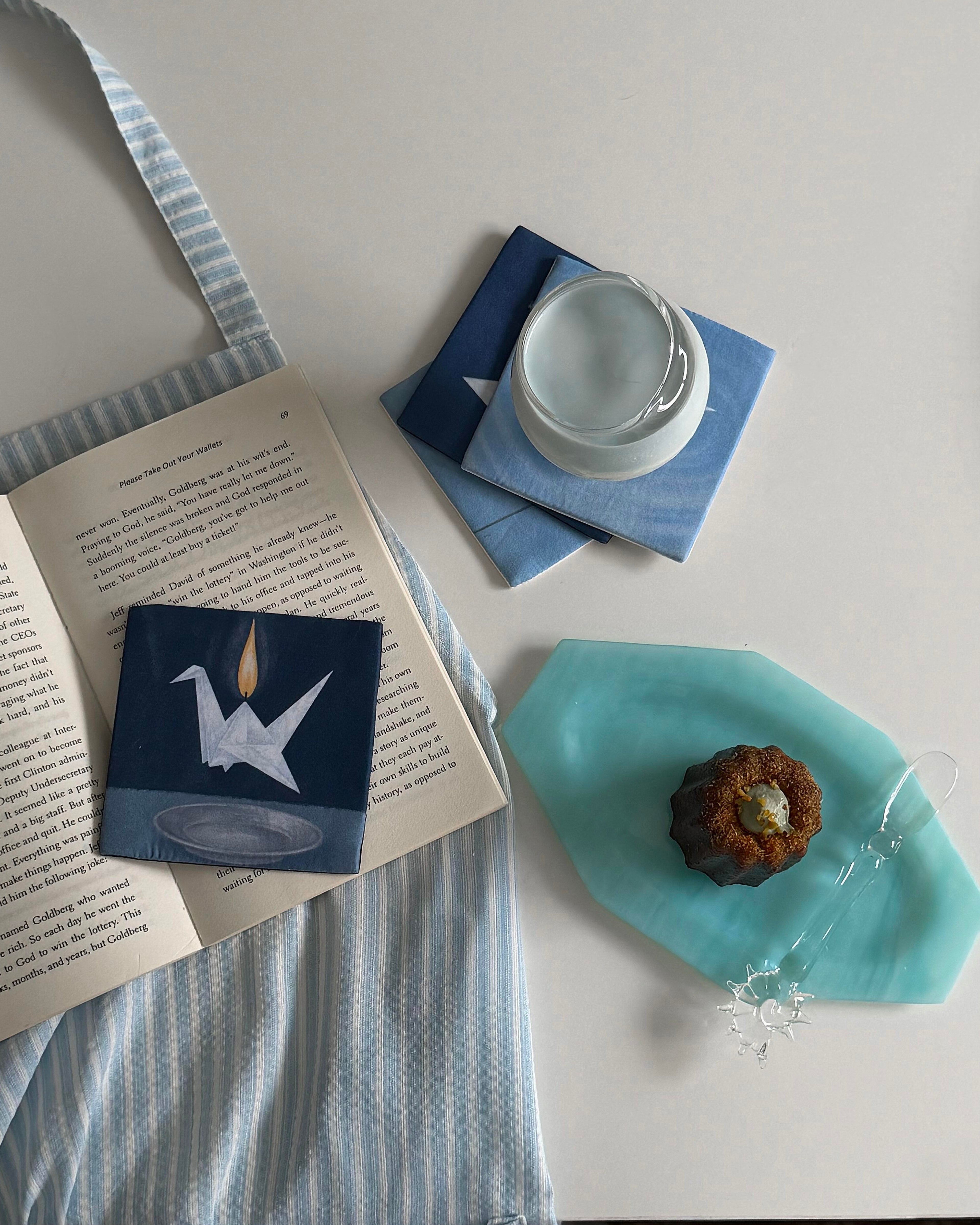 Blue and white coaster set styled with a linen napkin and teal dish
