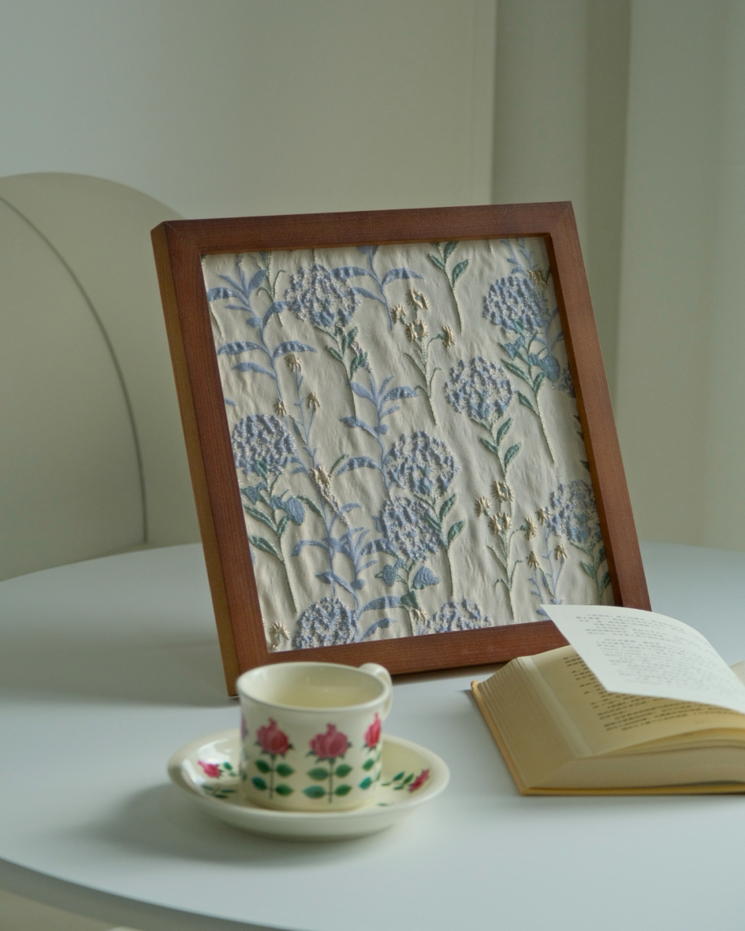 Detail of raised-texture blue and green hydrangea fabric in a walnut frame