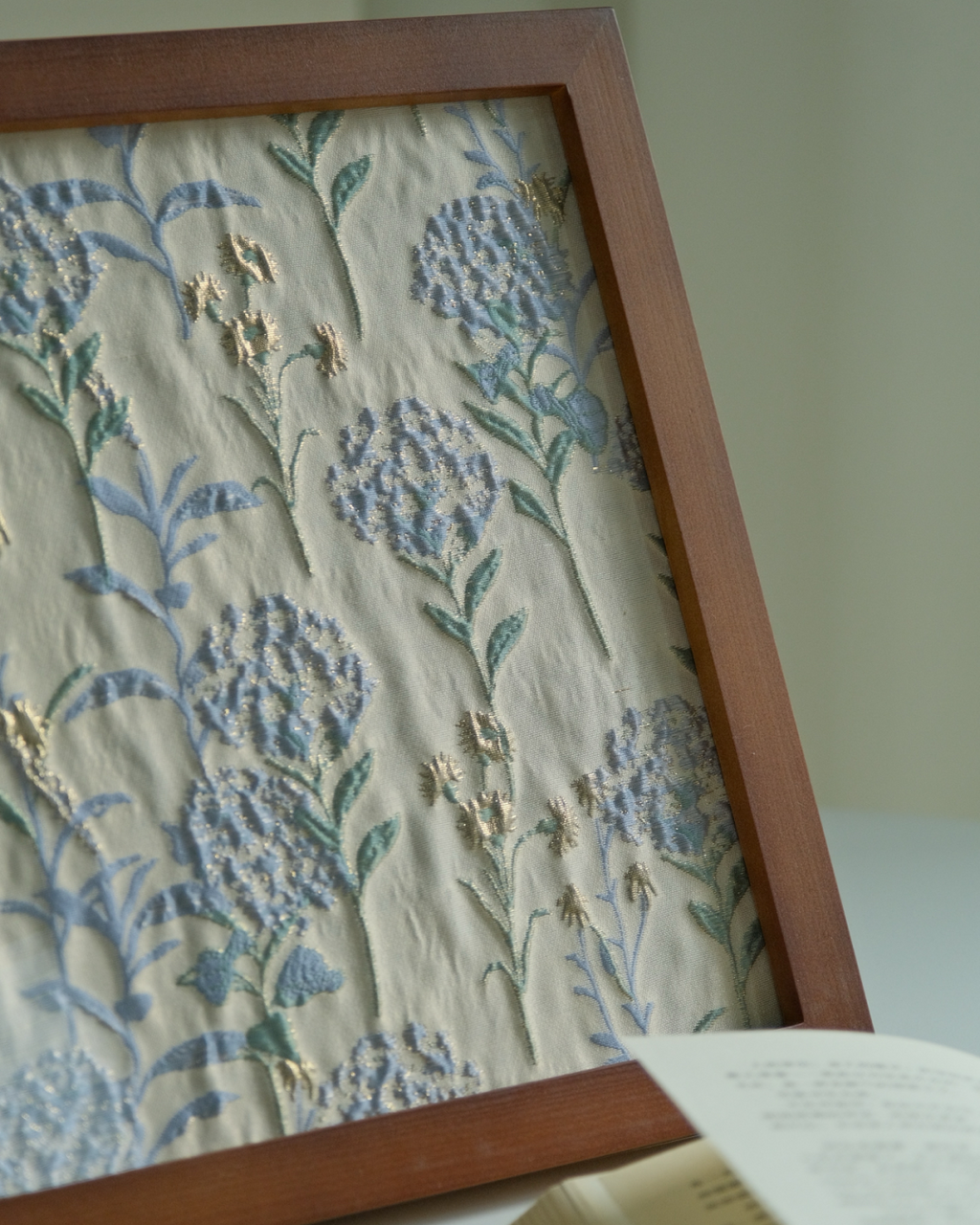 Close view of framed hydrangea fabric art with walnut frame on a tabletop