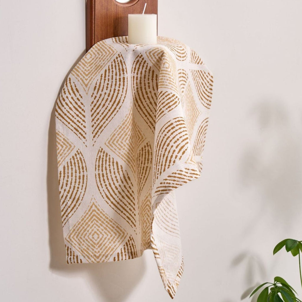 Woven cloth with geometric pattern hanging on a wooden hook against a white wall.