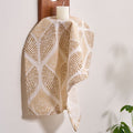 Woven cloth with geometric pattern hanging on a wooden hook against a white wall.