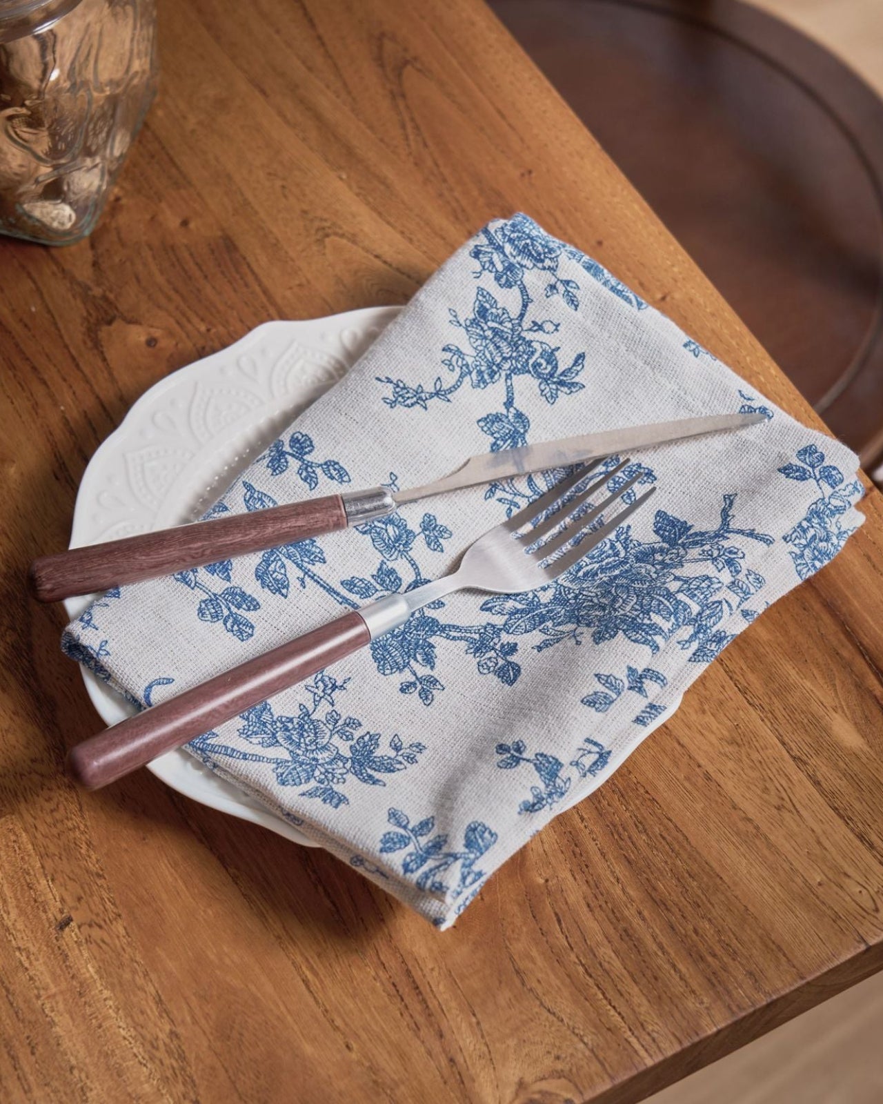 Fork and knife on a floral-patterned napkin on a wooden table