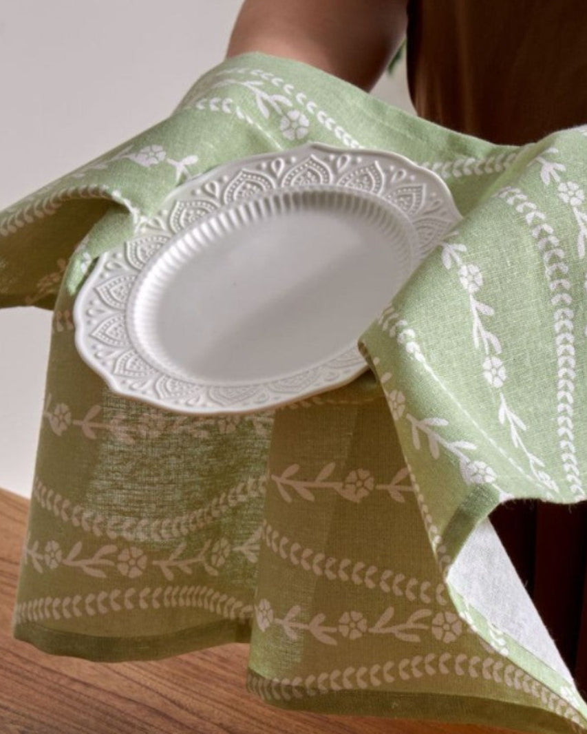 Sage green napkin holding a plate, botanical stripe print