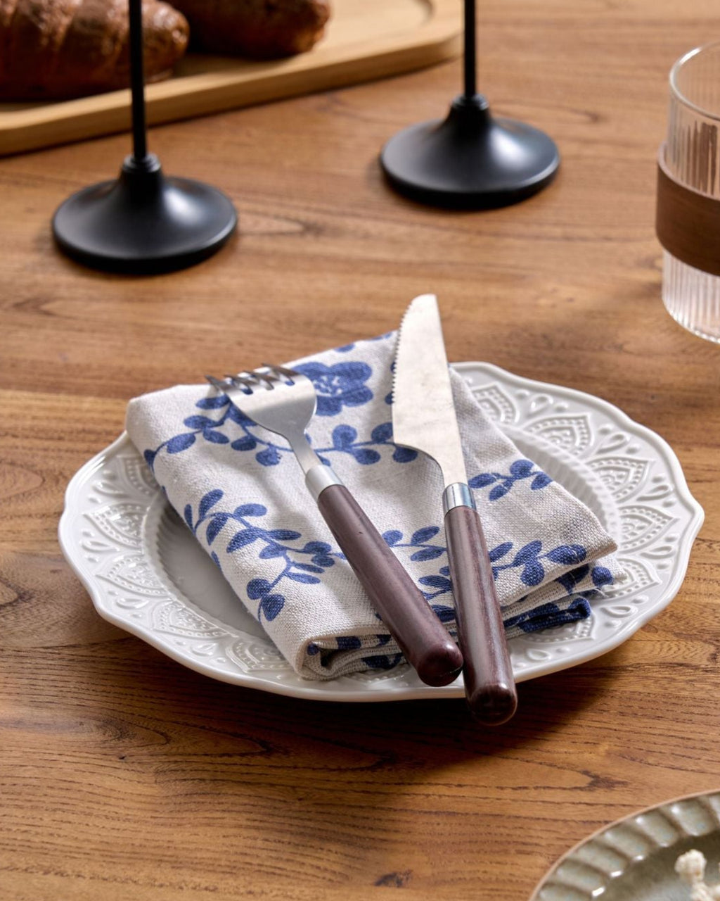 Blue floral napkin folded with cutlery on a plate