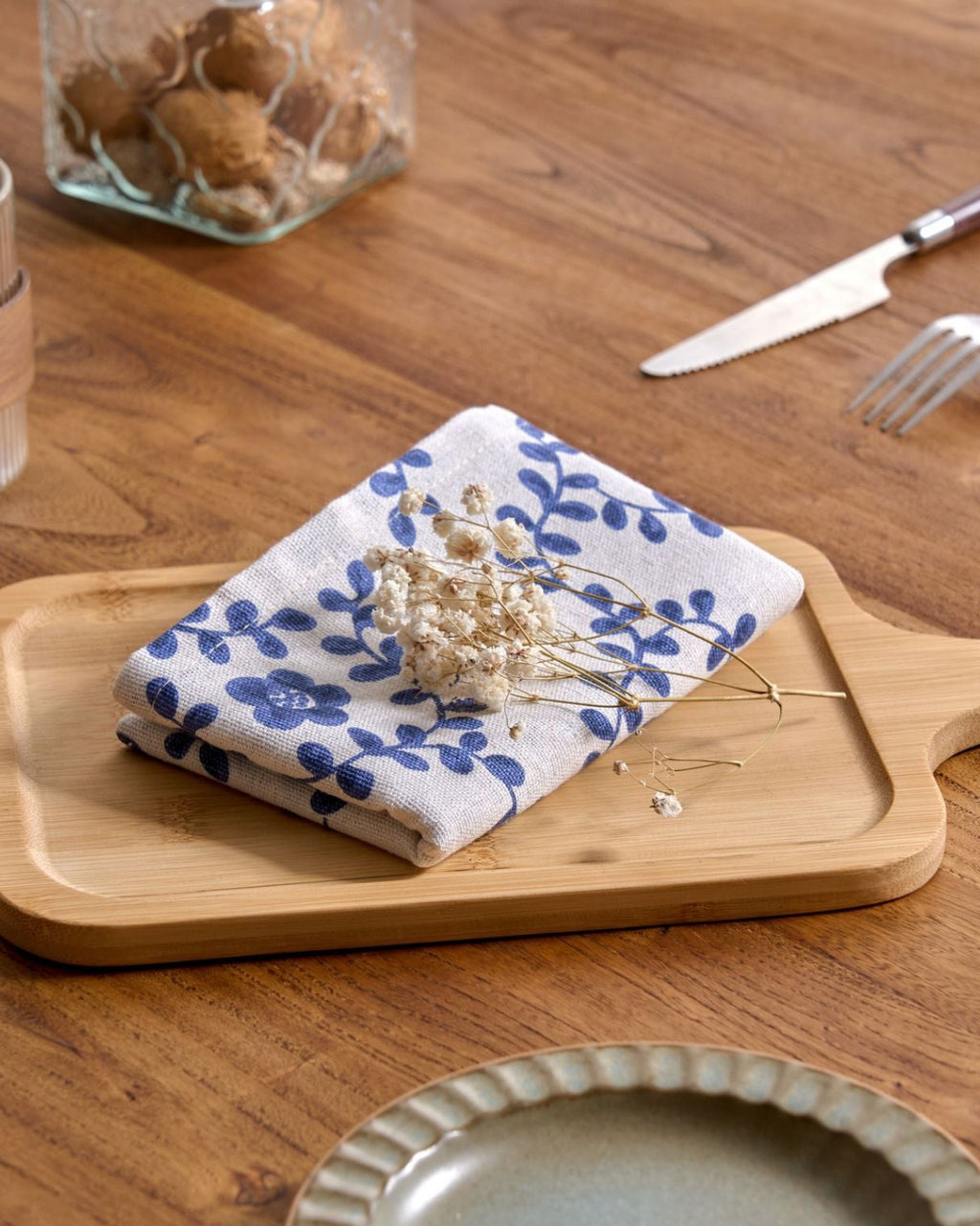 Folded blue floral cloth napkin on a wood board