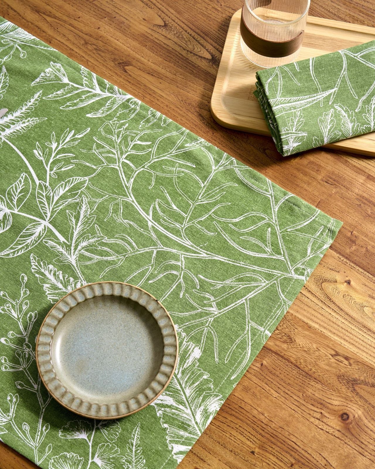 Green leaf-patterned placemat on a wooden table with a ceramic bowl.