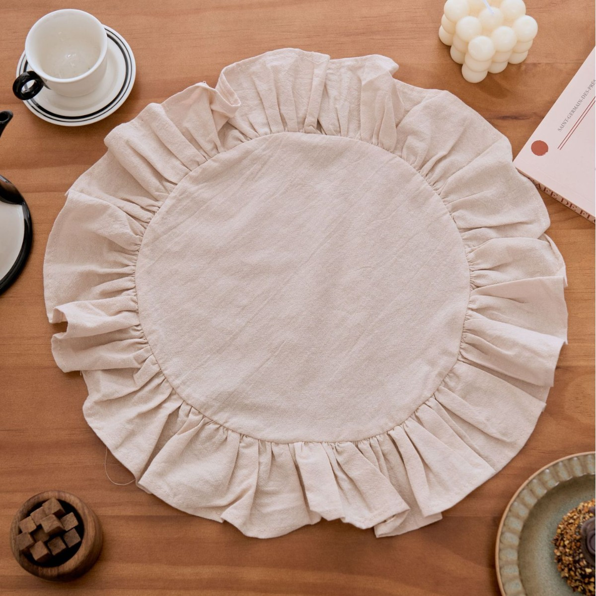 Round beige placemat with ruffled edge on a wooden table