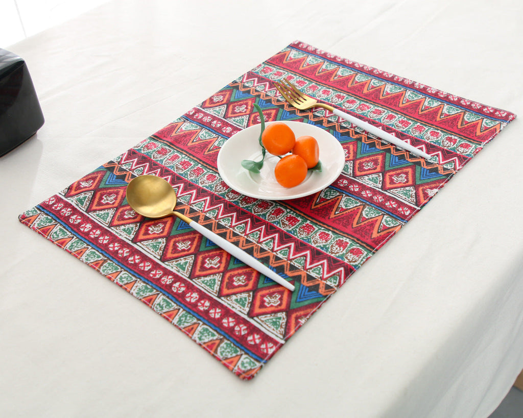 Colorful patterned placemat on a table with a plate of food and cutlery.