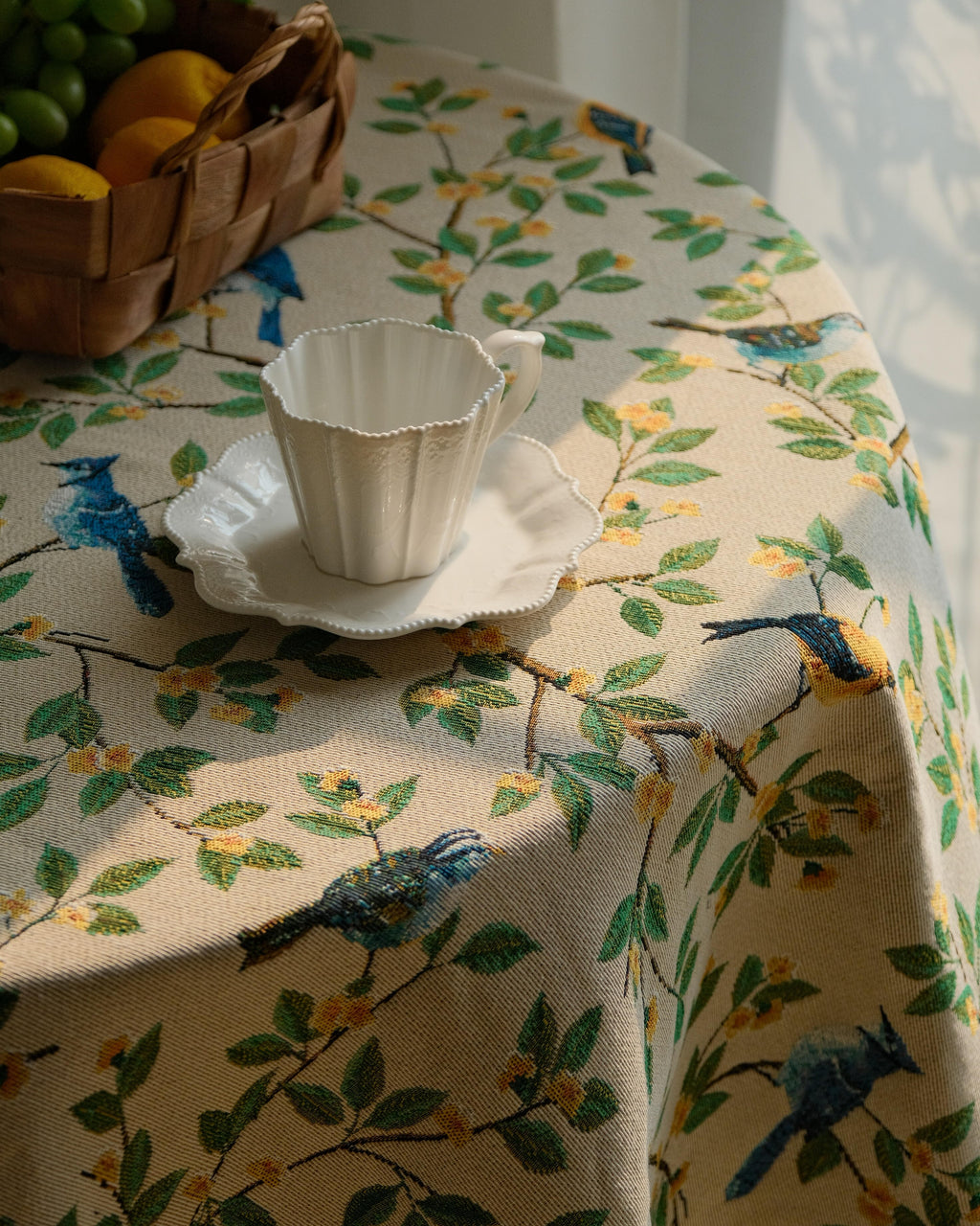 Close view of bluebird and floral print tablecloth with a teacup
