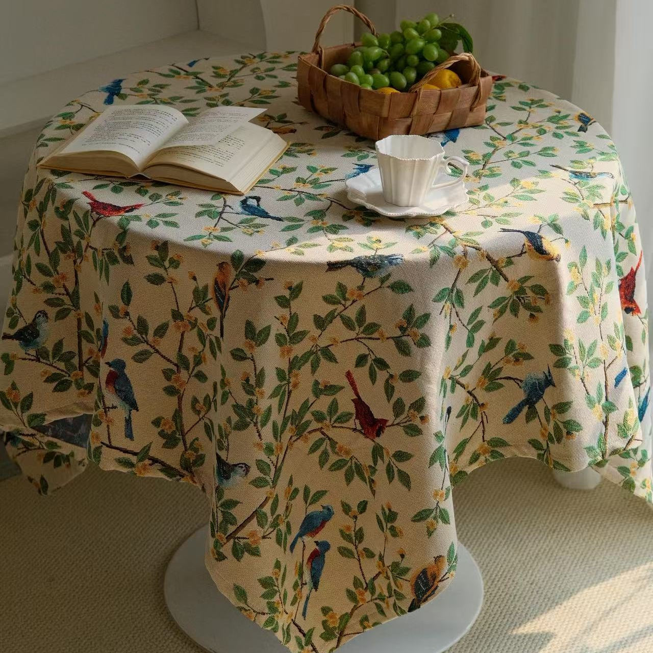 Bluebird floral tablecloth styled with a teacup and open book on a round table