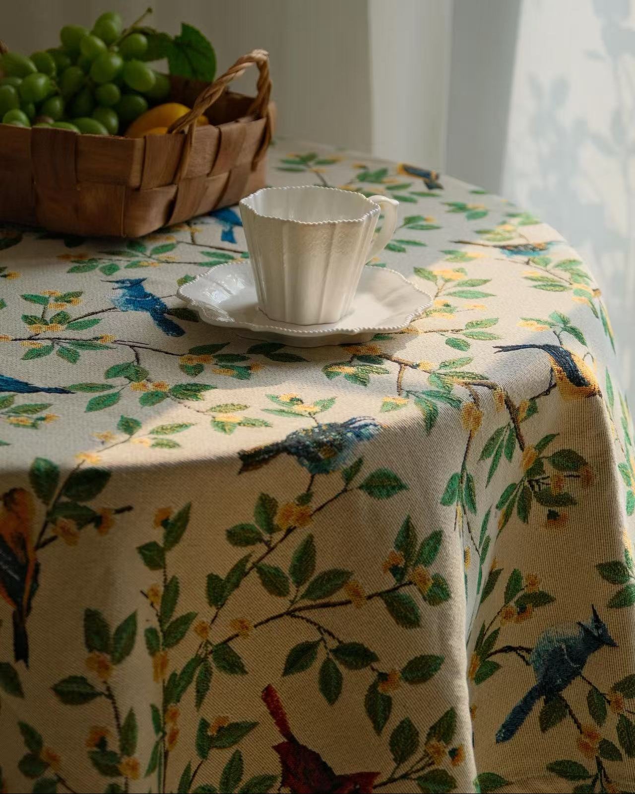 Bluebird Garden floral tablecloth draped over a round table with a fruit basket