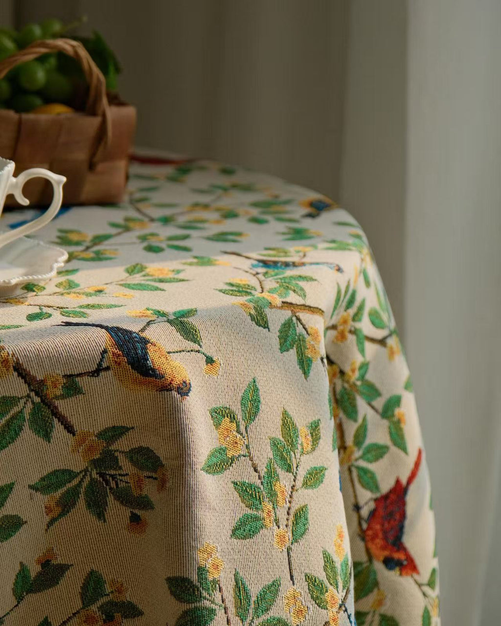 Bluebird Garden tablecloth detail showing birds and leaves against curtain light
