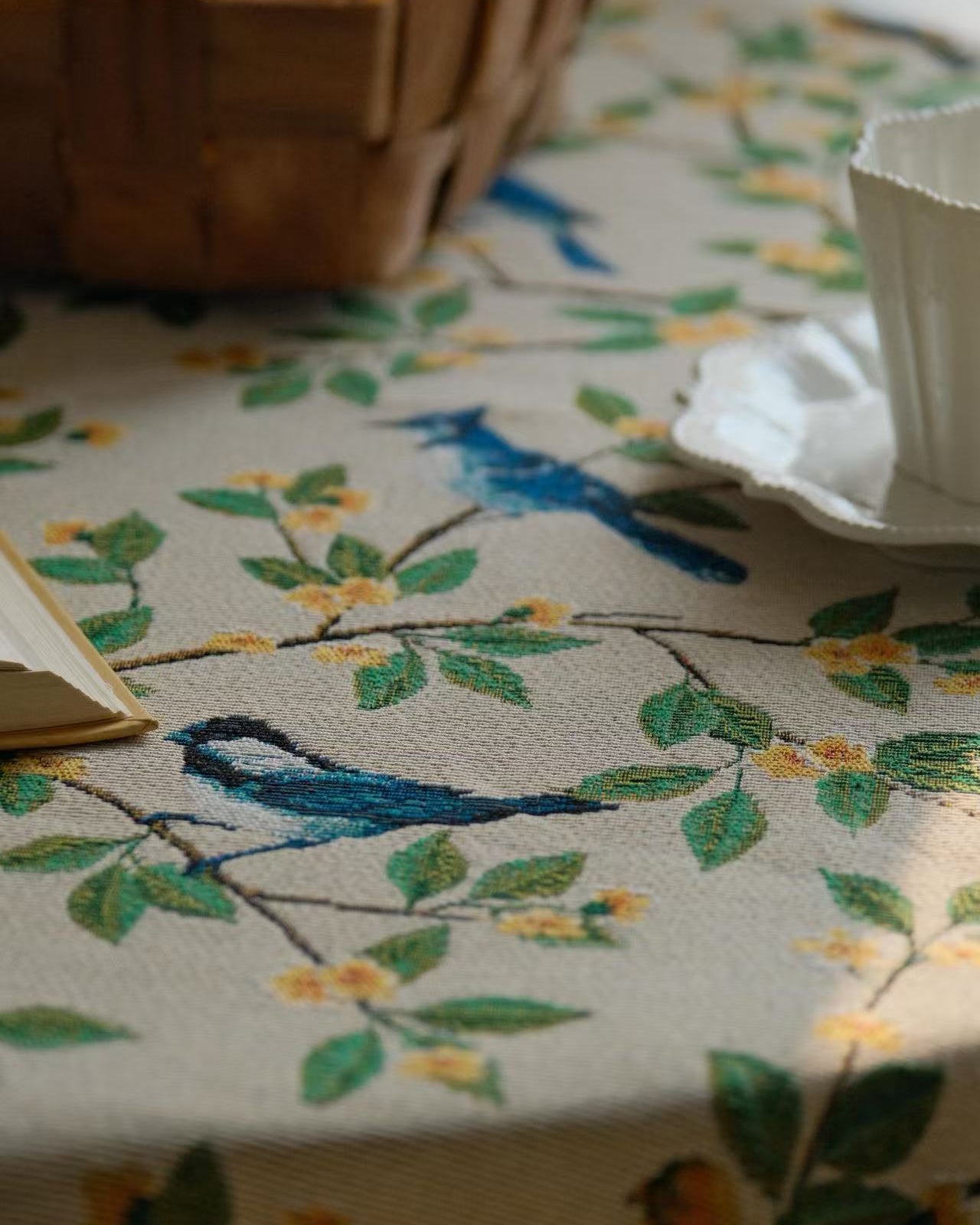 Bluebird floral tablecloth draped over table edge with folded napkin