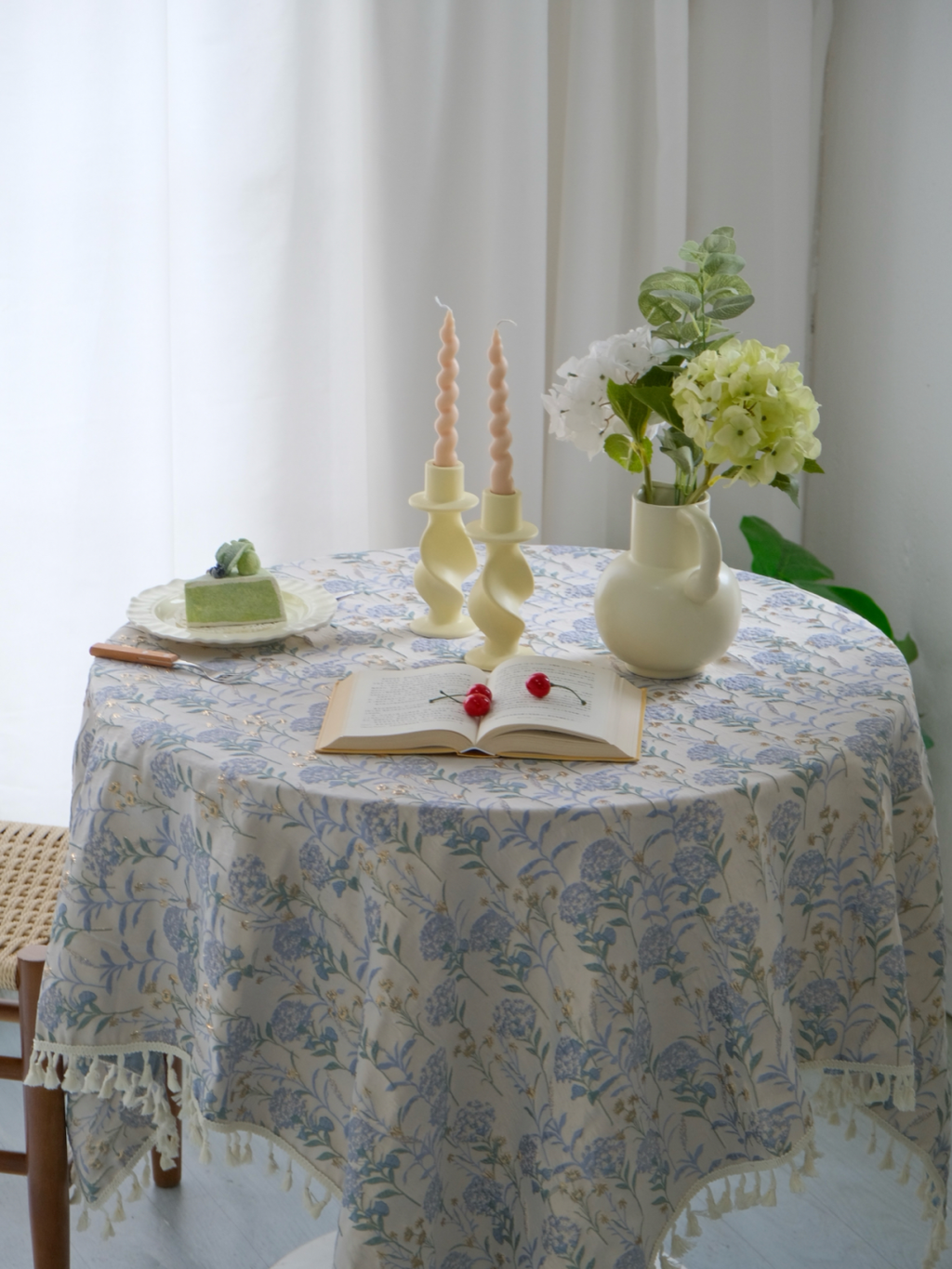 Blue floral tablecloth draped square on a round table, tassels