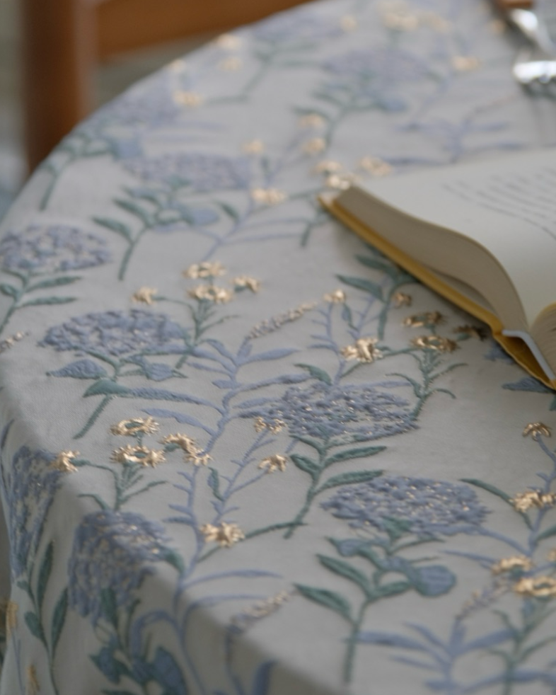 Floral-patterned tablecloth with an open book on a wooden chair.