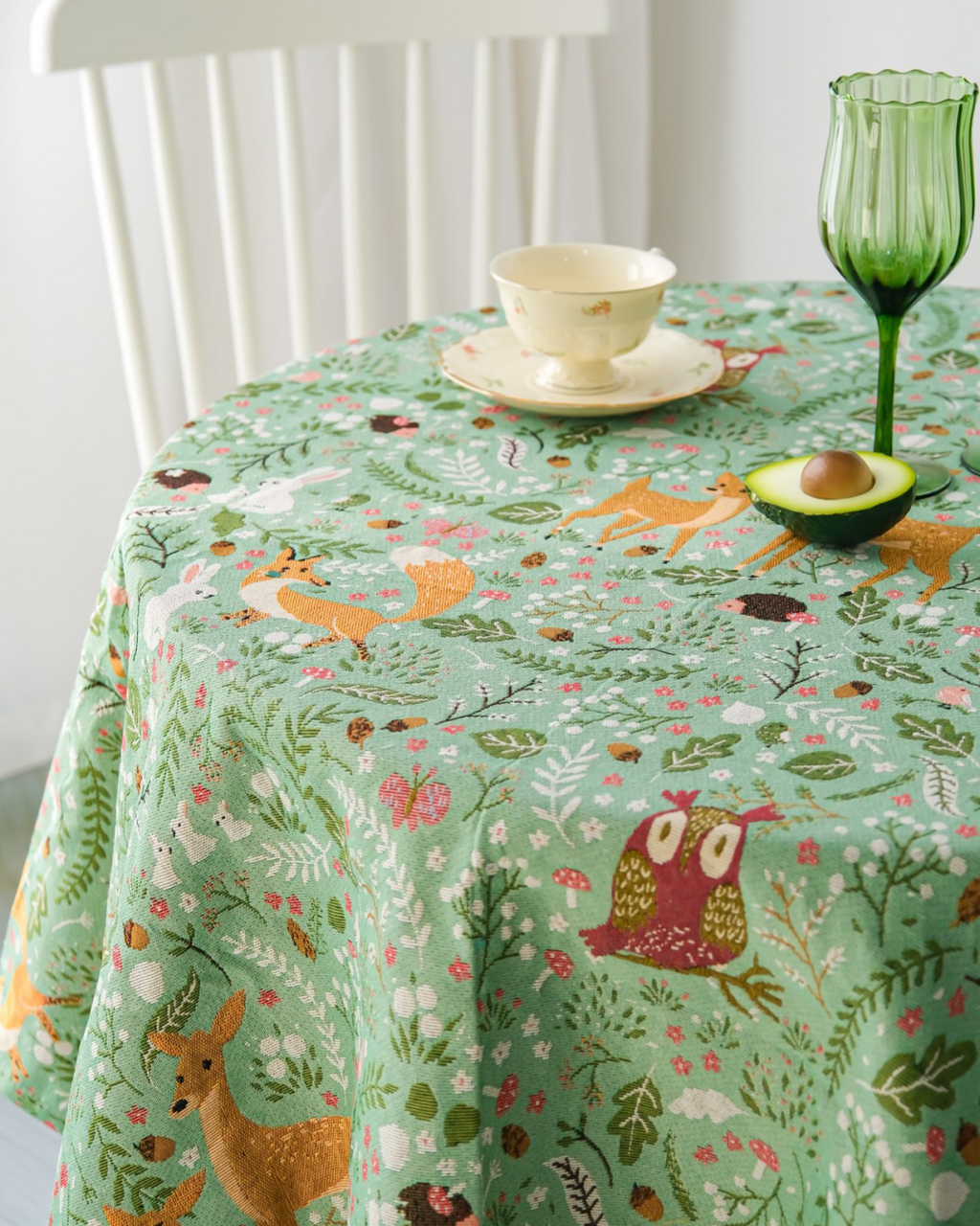 Woodland Fox and Deer tablecloth on a round table with a teacup and green glass