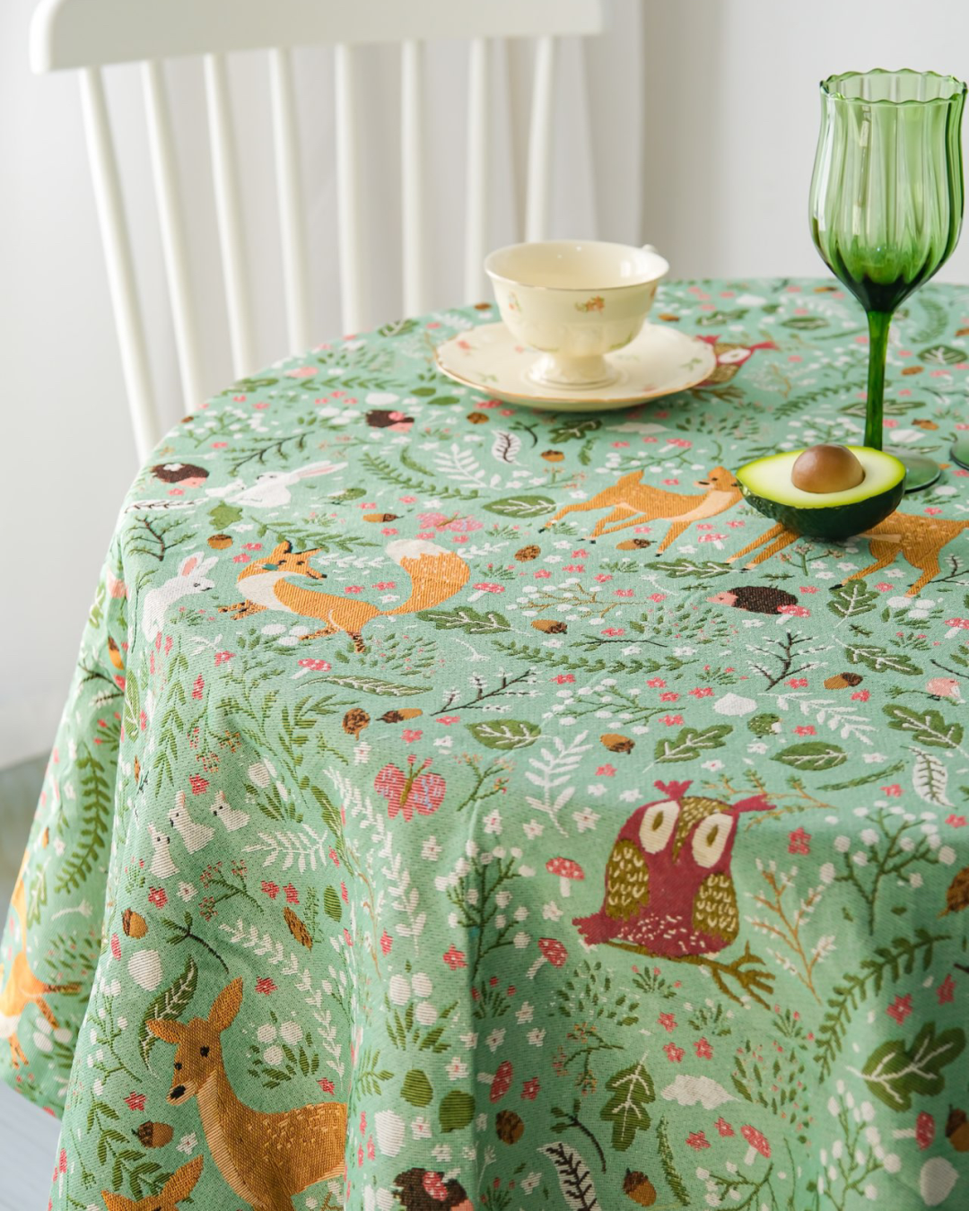 Woodland Fox and Deer tablecloth on a round table with a teacup and green glass