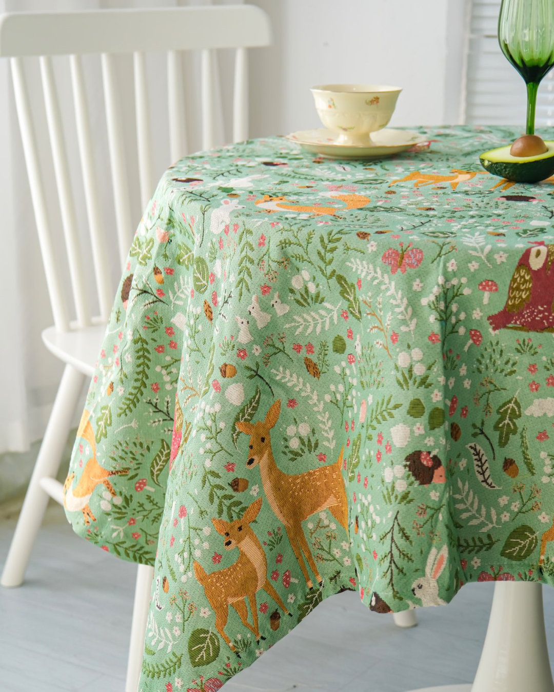 Woodland Fox and Deer tablecloth on a round table by a white chair