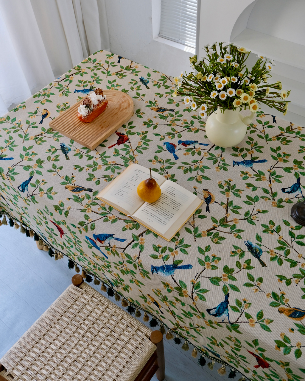 Bluebird floral tasseled tablecloth styled with a pastry and open book