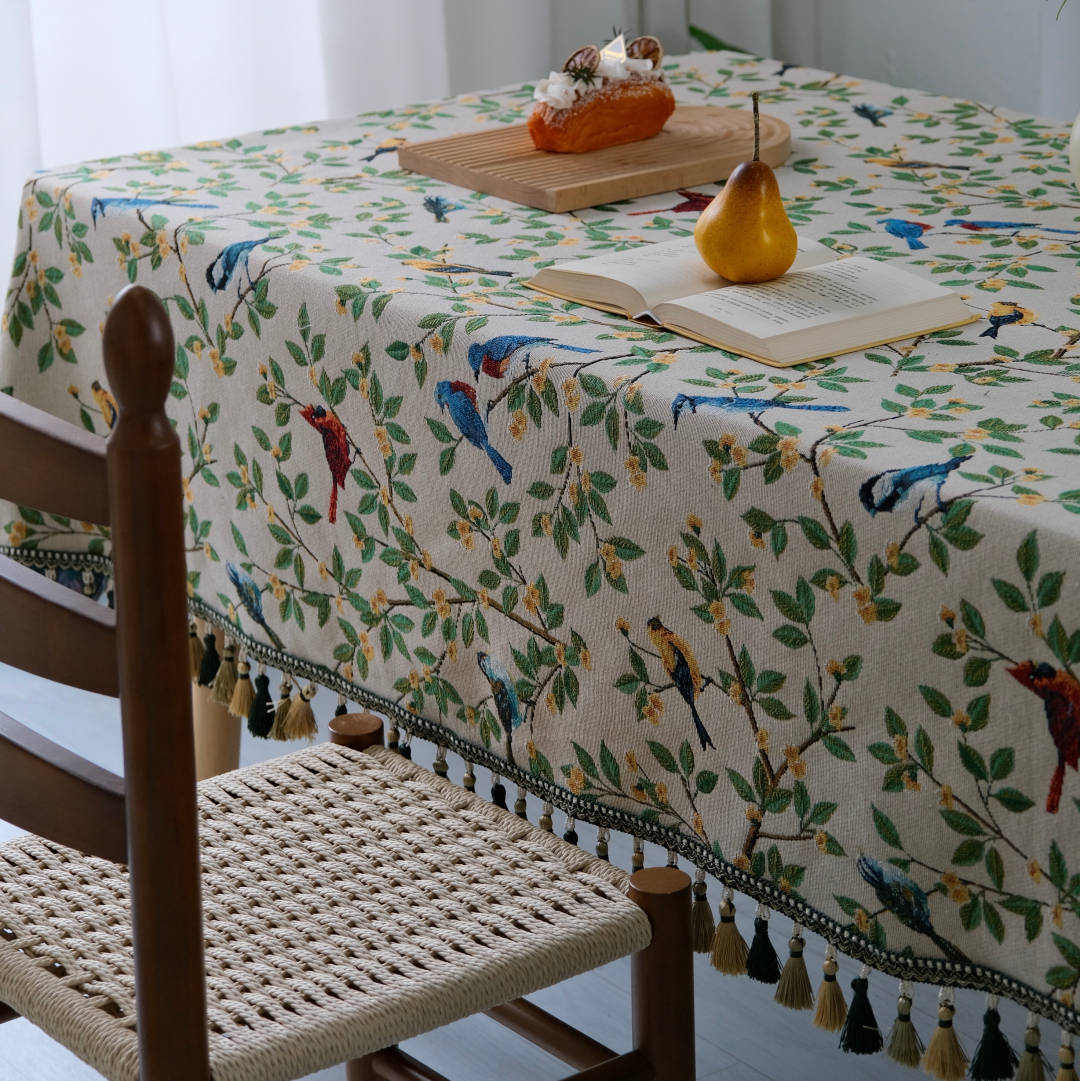 Bluebird Garden tasseled tablecloth on a rectangular table with woven chairs