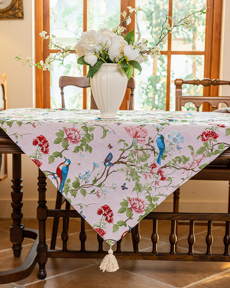 Rose Garden tablecloth with tassel trim on a dining table by a window