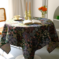 Dark floral meadow tablecloth on a round table with flowers and candles
