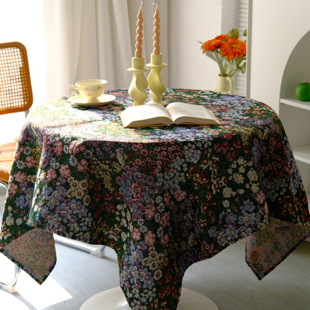 Dark floral meadow tablecloth on a round table with flowers and candles