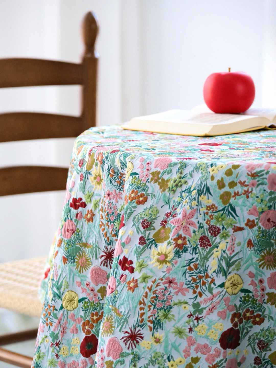 Bright floral garden tablecloth on a round table with a red apple