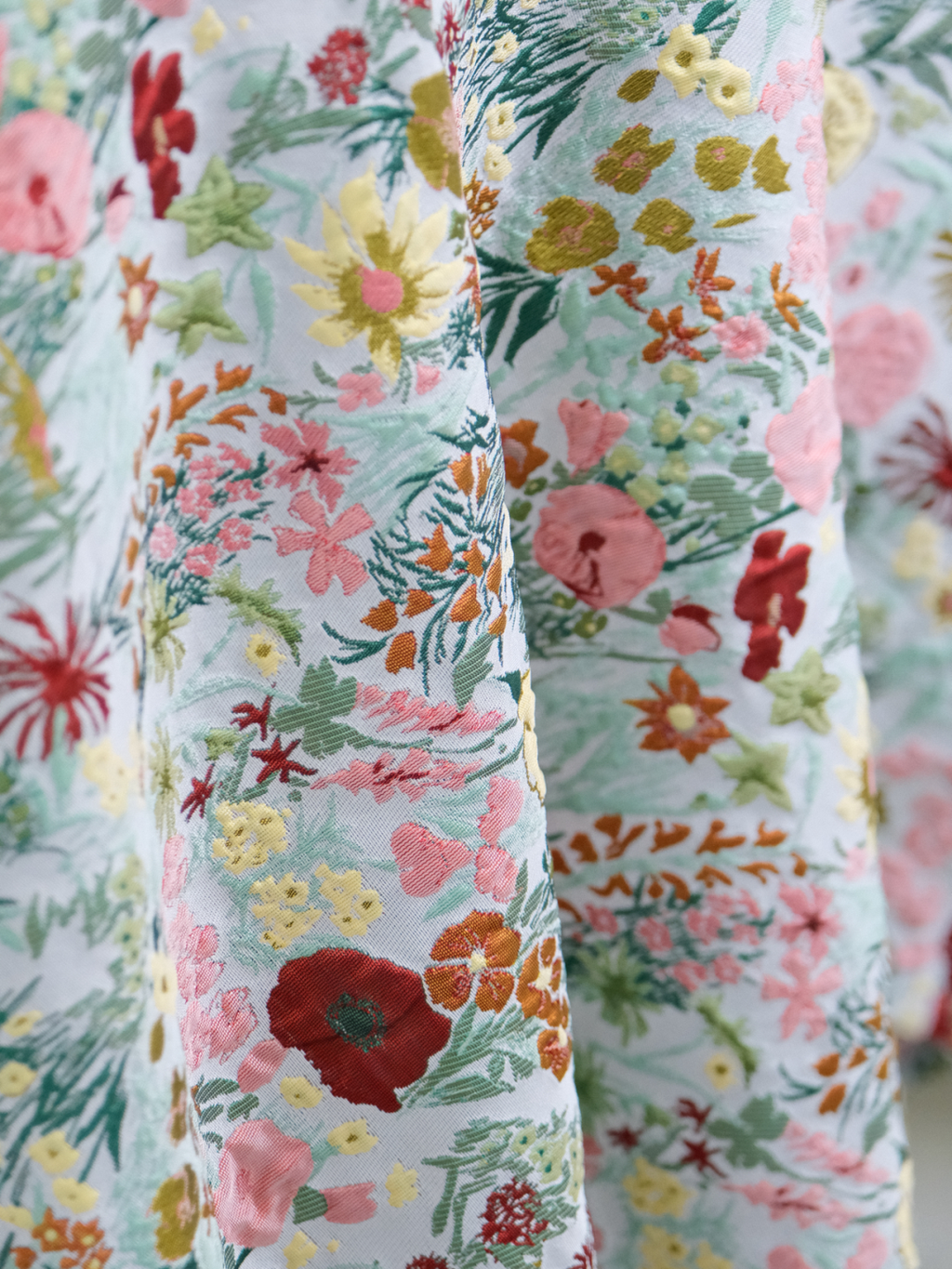 Bright floral tablecloth draped over table edge with pink blooms