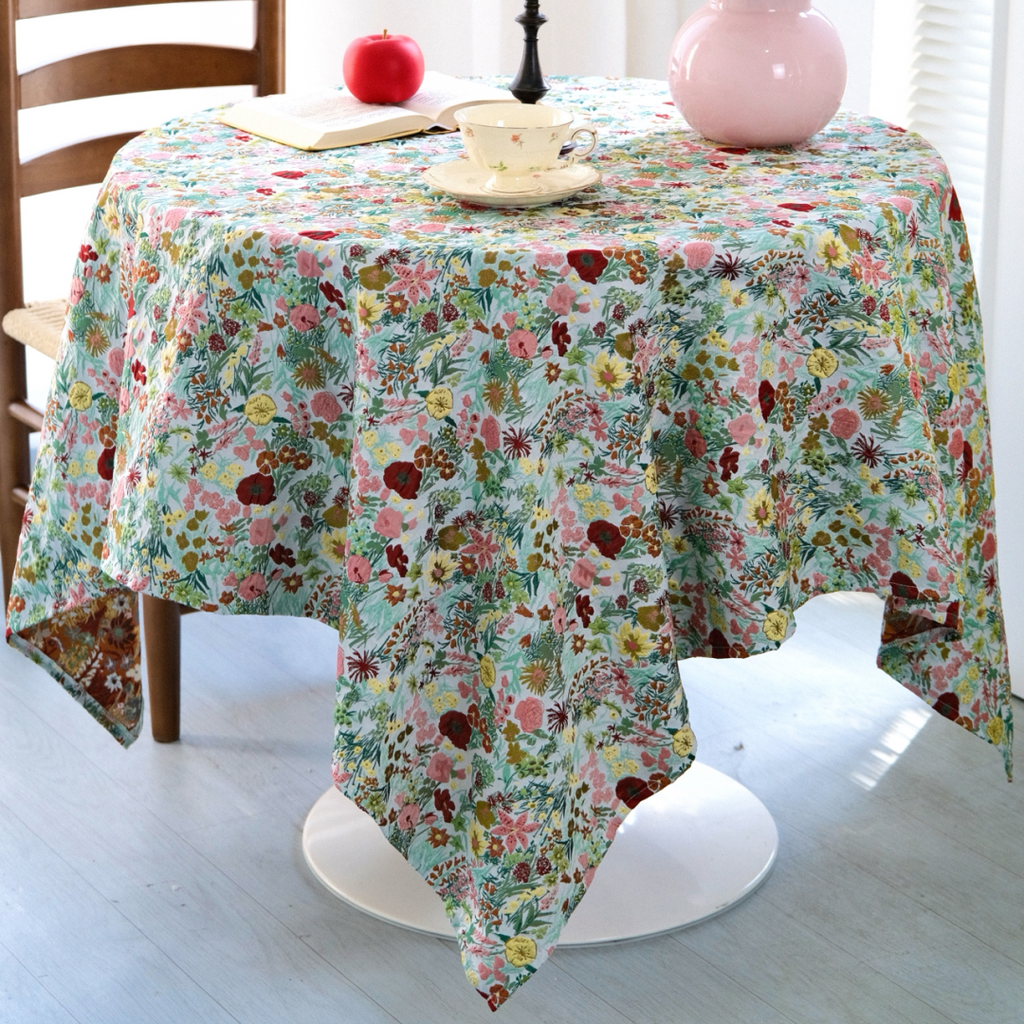 Bright floral garden tablecloth on a table with candles and roses