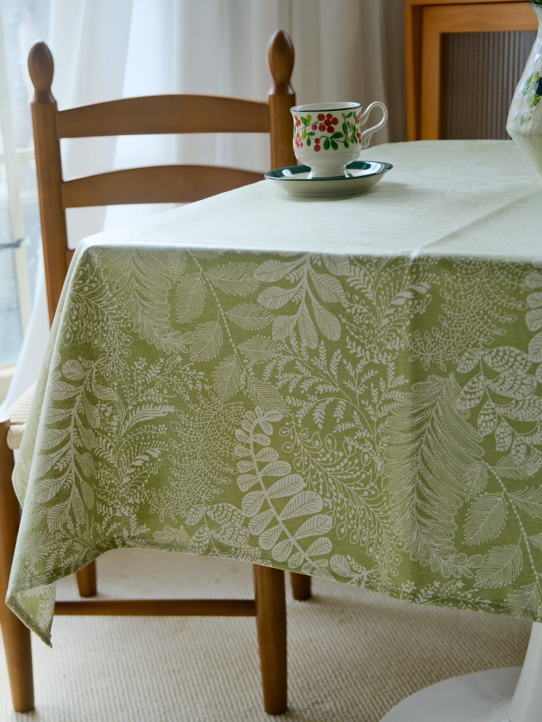 Sage green botanical leaf pattern tablecloth on farmhouse dining table