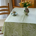 Sage green botanical tablecloth styled with flowers and ceramic tableware