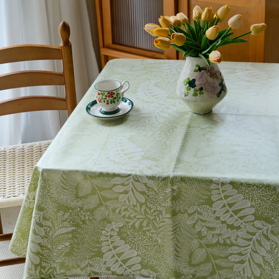 Sage green botanical tablecloth styled with flowers and ceramic tableware