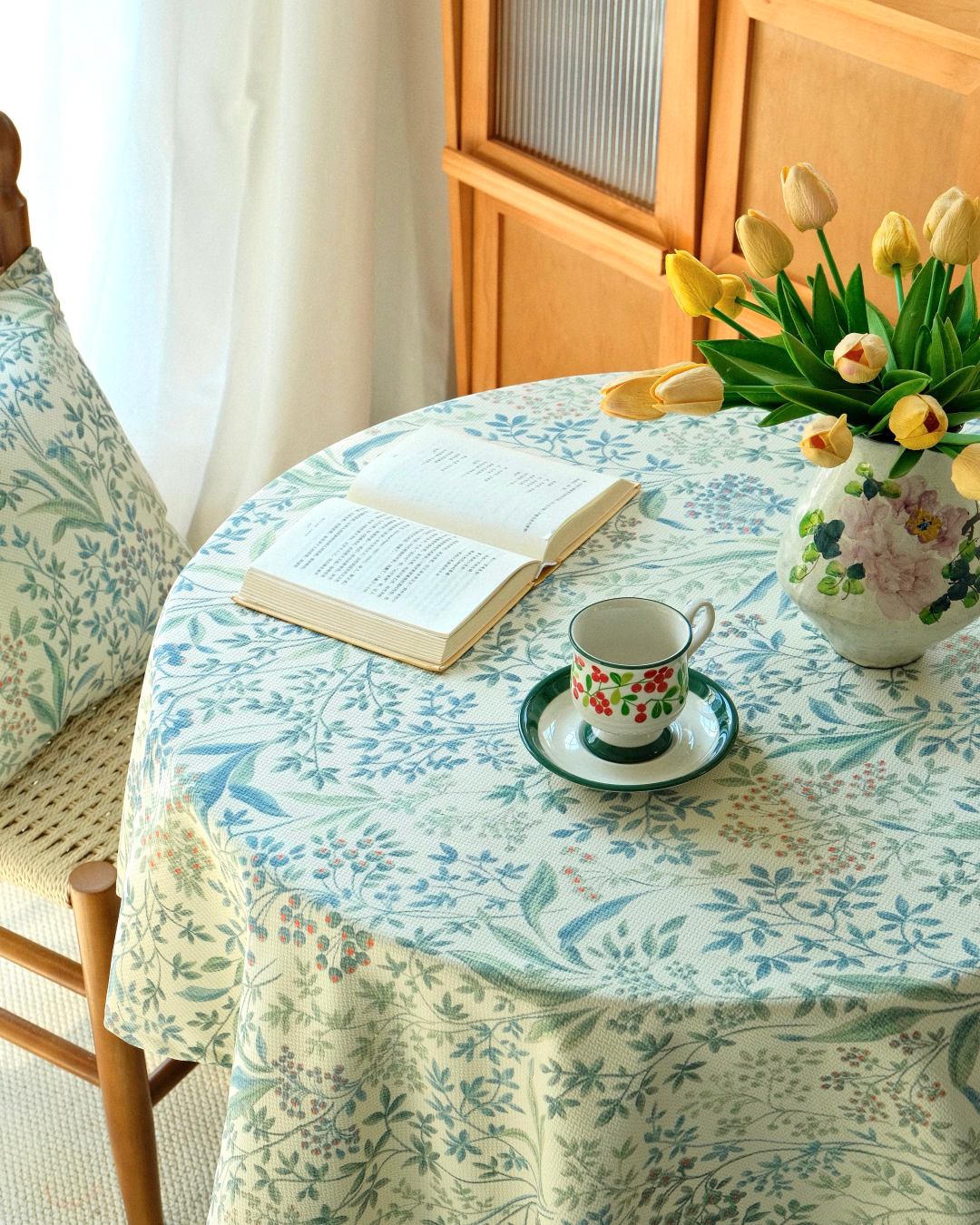 Blue botanical tablecloth styled on a round dining table with flowers